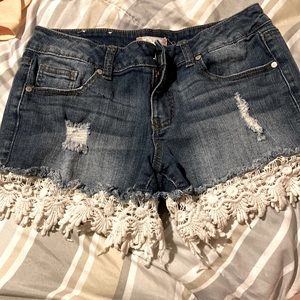 Blue Jean shorts with width width hand made designs at the bottom.